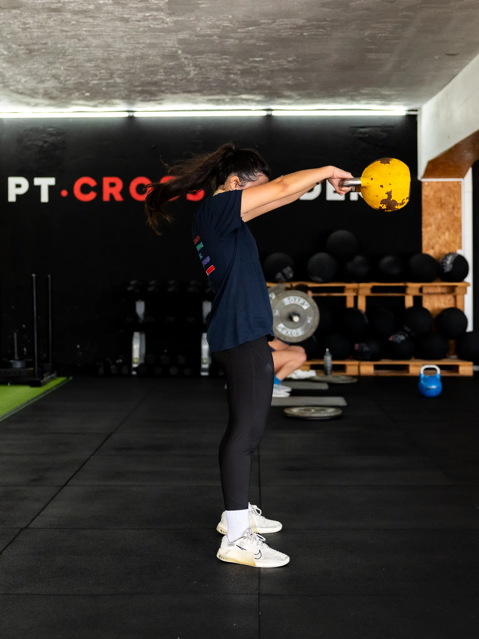 Atleta a fazer swing com kettlebell em frente ao letreiro da PT Cross Academy