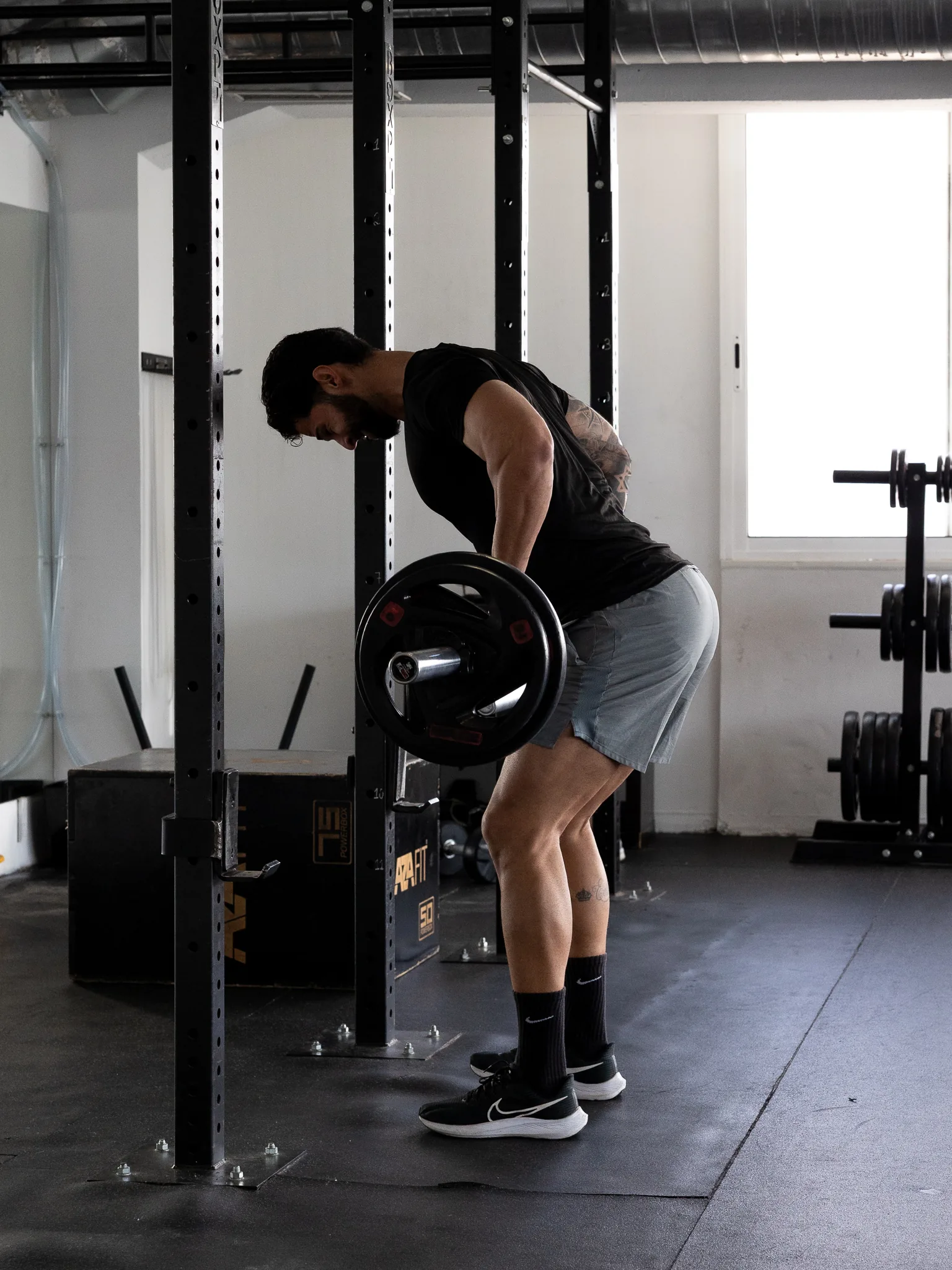Atleta a fazer remada com barra na sala de musculação da PT Academy