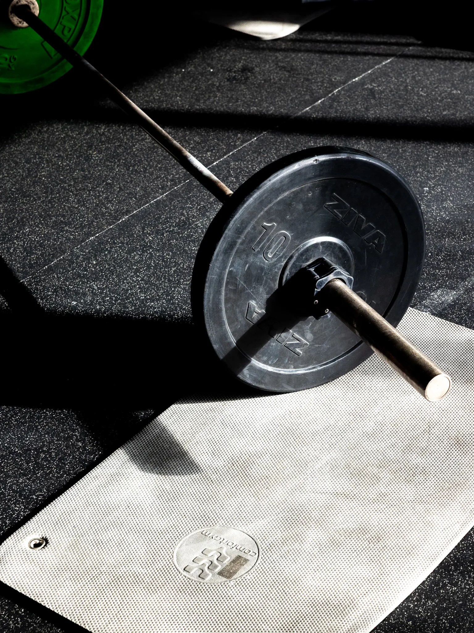Barra e disco de musculação em cima do tapete