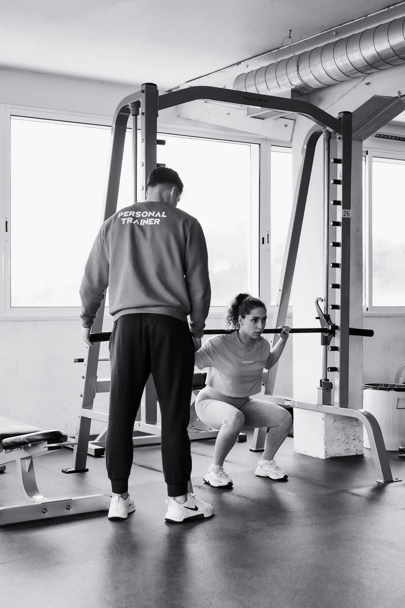 Personal trainer a acompanhar uma sócia num agachamento